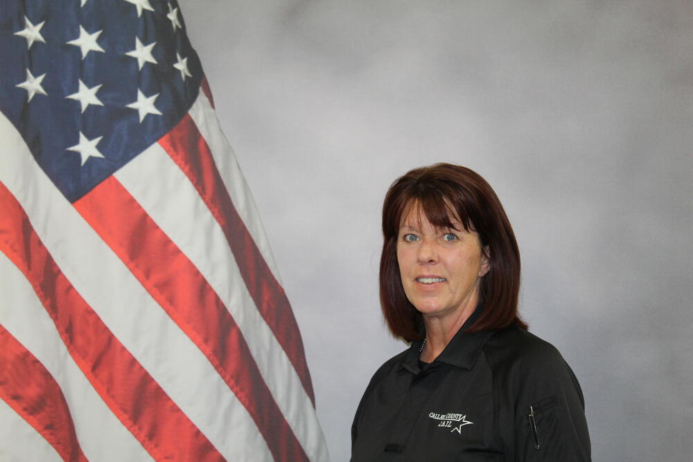 Lieutenant Melissa Ewens pictured in uniform in front of an American Flag.